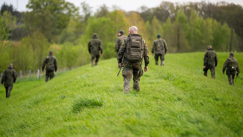 Die Soldaten marschieren über den Deich.