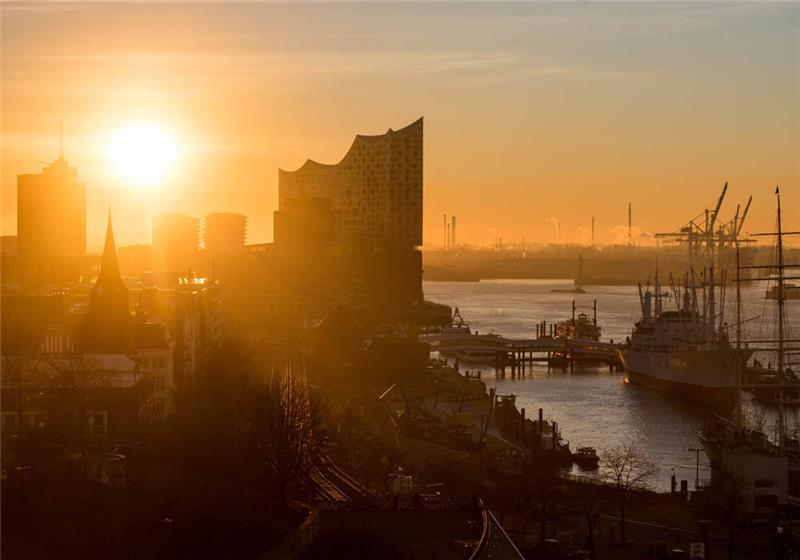 Die Sonne geht am Morgen am Hafen über Sankt Pauli (l) und der HafenCity (h) mit der Elbphilharmonie (M) auf. Foto: Daniel Bockwoldt/dpa