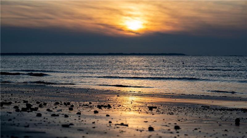 Die Sonne geht am Strand der Insel Langeoog über der Nordsee unter.