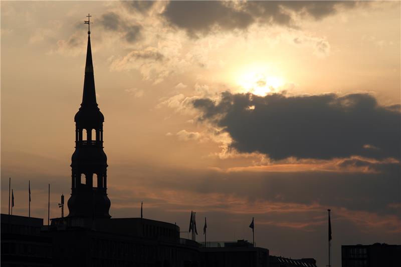 Die Sonne geht neben dem Turm der Hauptkirche St. Katharinen in Hamburg auf. Symbolfoto Bodo Marks/dpa