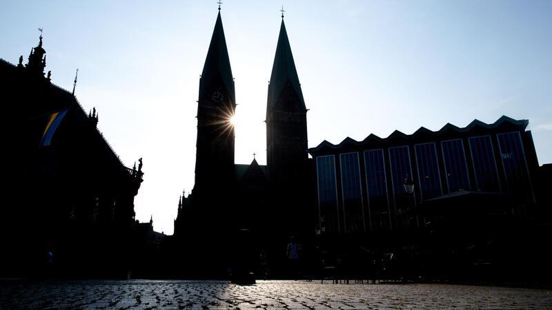 Die Sonne scheint am blauen Himmel hinter den Türmen des St.-Petri-Dom am Bremer Marktplatz.