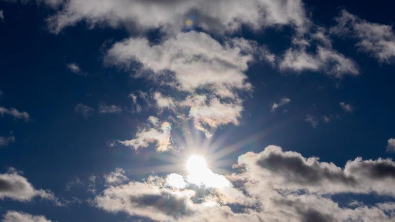 Die Sonne scheint zwischen Wolken hindurch.