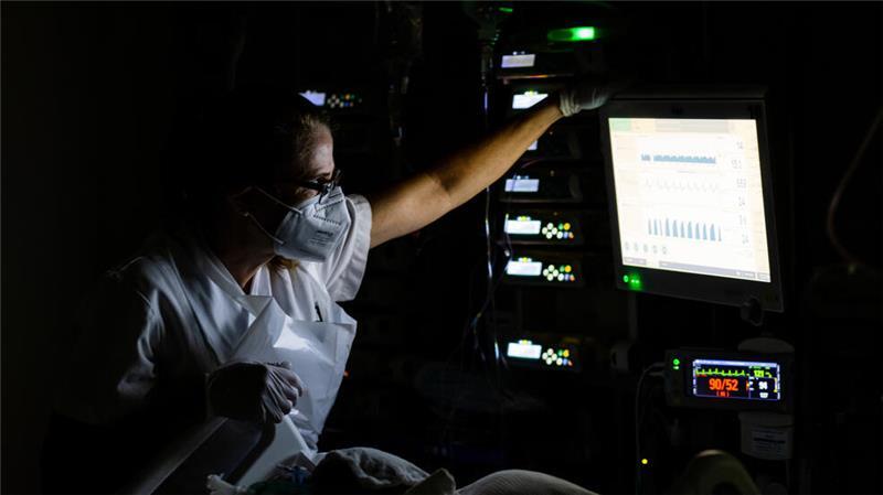 Die Stationsleiterin einer Intensivstation prüft Herzfrequenz und Blutdruck eines Patienten an einem Monitor über seinem Bett.