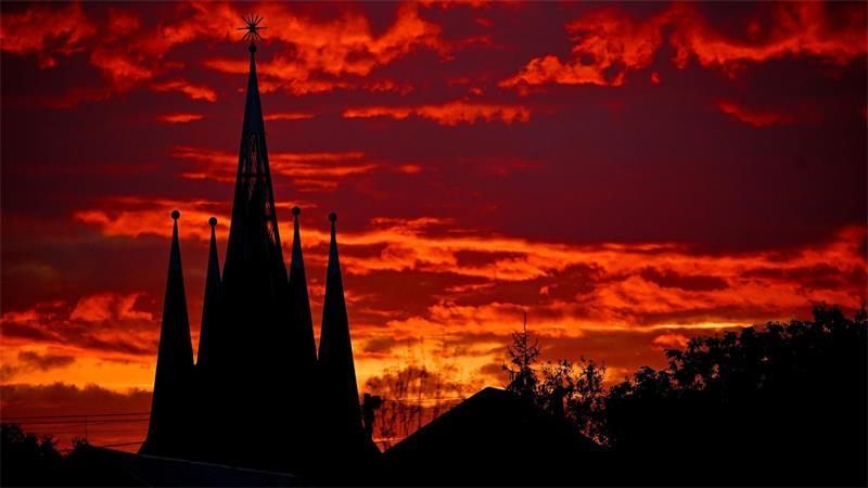 Die Türme der protestantischen Kirche von Teglaskert in in Ungarn zeichnen sich vor der untergehenden Sonne ab.