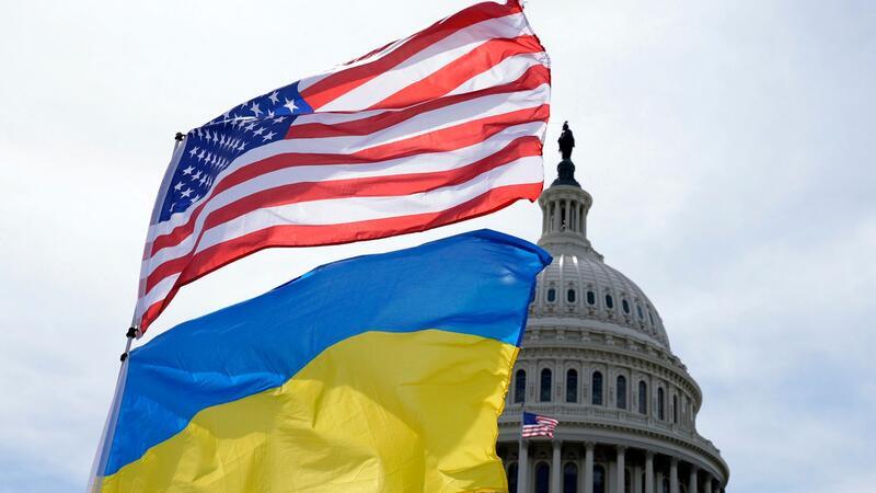 Die US-amerikanische und die ukrainische Flagge wehen vor dem Kapitol in Washington im Wind. Das Pentagon will Kiew bei der Luftverteidigung unterstützen und auch Artilleriemunition liefern.