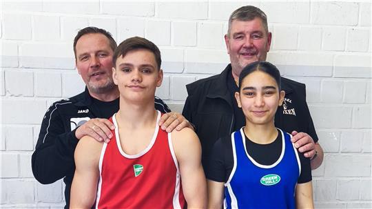Orlando Smit und Lara Alahmad in Boxkleidung mit zwei Trainern vor einer weißen Wand.