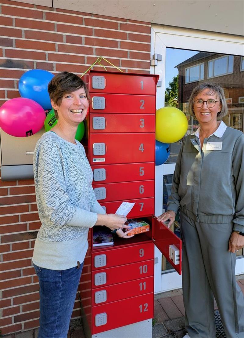 Die Vorsitzende des Fördervereins der Gemeindebücherei Steinkirchen, Nicole Nehring, mit Büchereileiterin Petra Abel (rechts) vor der neuen Abholstation in Steinkirchen.
