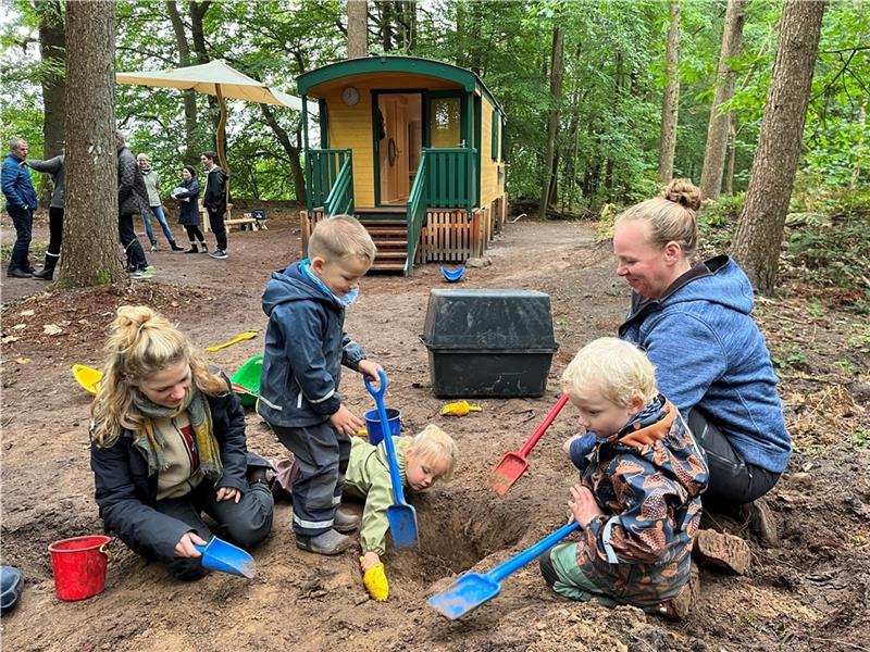 Die Waldkindergarten-Erzieherinnen Jana Grudzinski und Ava von Horn unterstützen Ole, Frieda und Henry bei der Schatzsuche im Nottensdorfer Wald (von links). Hinten steht der Bauwagen der DRK-Kita. Foto: Vasel