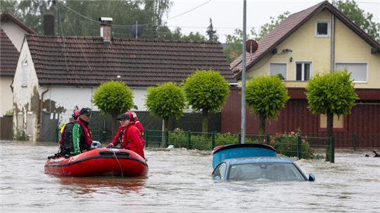 Die Wasserwacht fährt mit einem Schlauchboot durch eine überflutete Straße. Nach den ergiebigen Regenfällen der letzten Tage gibt es Hochwasser in der Region.