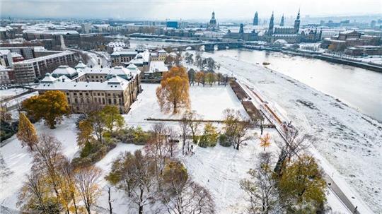 Die Wiesen am Elbufer vor der historischen Altstadt von Dresden sind mit Schnee bedeckt.