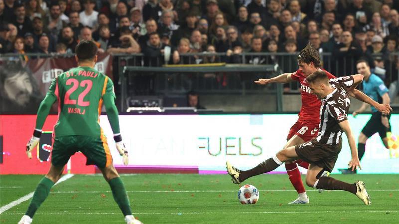 Die aus Sicht von Alexander Blessin strittige Szene vor dem Strafstoß: Kölns Jakub Kaminski (M,) und Karol Mets (FC St. Pauli) kämpfen um den Ball.