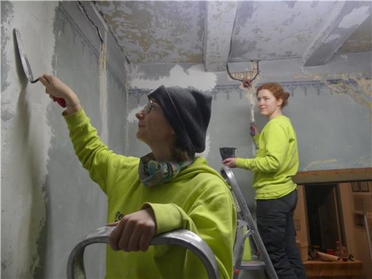 Die beiden FSJlerinnen Meilinn Flüh (links) und Frederike Holz von der Jugendbauhütte renovieren im Schulmuseum. An zwei Wänden unter der Decke wurde ein kleiner Fries entdeckt. Foto: Knappe