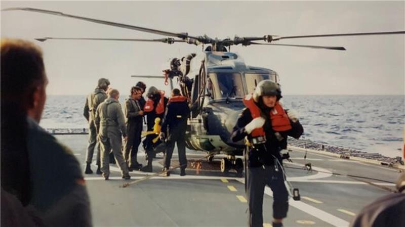 „Ich hörte einen Knall“: Pilot erinnert sich an Helikopter-Absturz auf See Die deutsche Besatzung wartete auf der Fregatte Niedersachsen auf die verunglückte Crew und war erleichtert, als sie sie lebend in Empfang nehmen konnte (vorne Pilot Stephan S., in Gelb das gerettete Maskottchen Flat Eric).