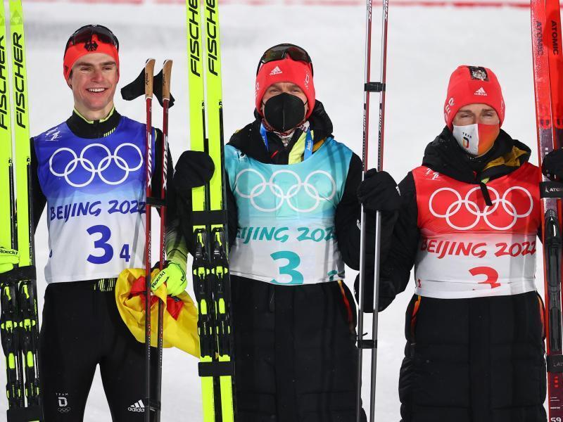 Die deutschen Nordischen Kombinierer Vinzenz Geiger (von links), Julian Schmid und Manuel Faisst jubeln über die Silbermedaille. Foto: Daniel Karmann/dpa