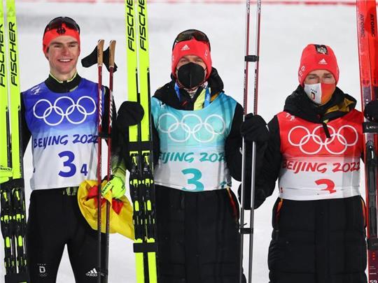 Die deutschen Nordischen Kombinierer Vinzenz Geiger (von links), Julian Schmid und Manuel Faisst jubeln über die Silbermedaille. Foto: Daniel Karmann/dpa