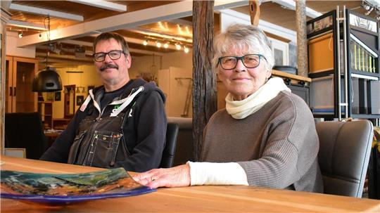 Ralf Wendler und Renate Wendler sitzen an einem Tisch in ihrer Möbelhalle.