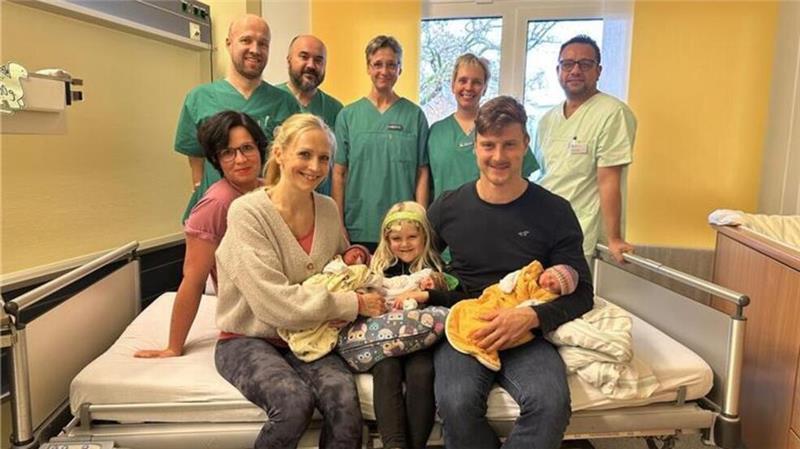 Die glückliche Familie mit ihren Drillingen, umgeben vom Team der Geburtshilfe, Kinderklinik und Kinderintensivstation.