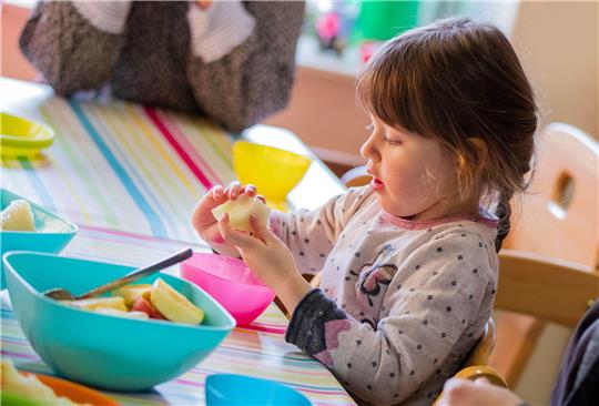 Die kleine Marlene isst zum Frühstück ein Apfelstück. Foto: Jens Büttner/dpa-Zentralbild/dpa