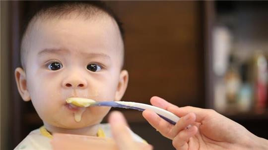 Ein Baby wird mit Brei gefüttert.
