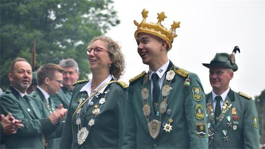 Die neue Schützenkönigin Silke Deede und der neue Jungschützenkönig Mark Schomacker marschieren vorbei am Spalier und durch grüne Rauchschwaden, begleitet von Präsident Dirk Holthusen (rechts).