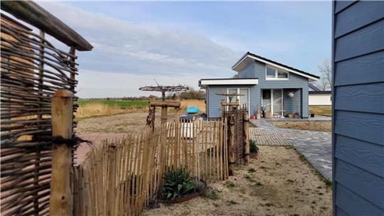 Die taubenblaue Fassade der drei kleinen Steinhäuser erweckt nur den Anschein einer Gebäudehülle aus Holz. Tatsächlich handelt es sich um ein Kunststoff-Zement-Gemisch.