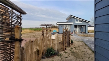 Die taubenblaue Fassade der drei kleinen Steinhäuser erweckt nur den Anschein einer Gebäudehülle aus Holz. Tatsächlich handelt es sich um ein Kunststoff-Zement-Gemisch.