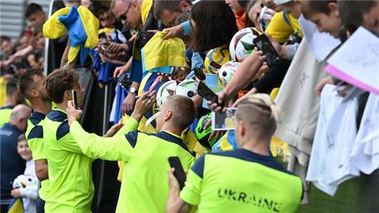 Die ukrainischen Nationalspieler geben nach dem öffentlichen Training Autogramme.