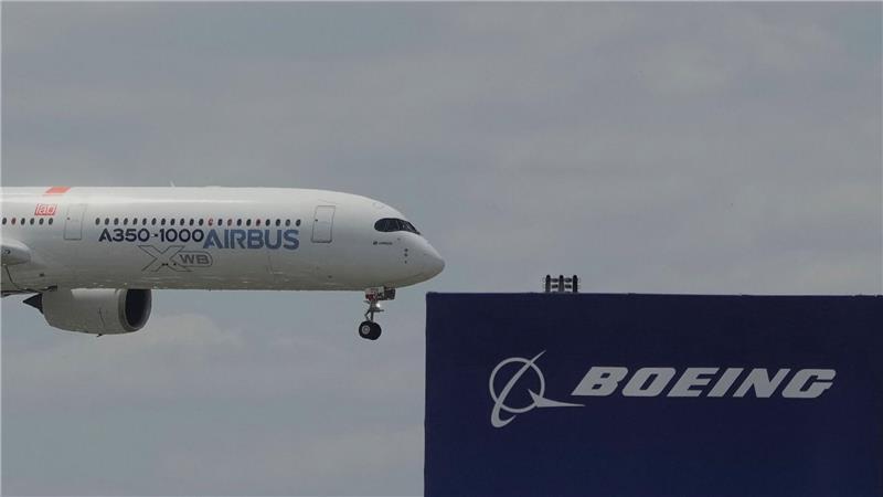 Die zwei großen Konkurrenten: Ein Airbus fliegt bei einer Vorführung auf der Luftfahrtmesse Salon du Bourget an einem Logo von Boeing vorbei.