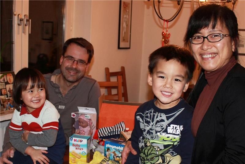 Die zweijährige An hat für ein kleines Mädchen Geschenke ausgesucht , der fünfjährige Lim für einen kleinen Jungen. Zusammen mit ihren Eltern, Diep und Jan Deichsel, packen sie jetzt zwei Päckchen. Foto Richter