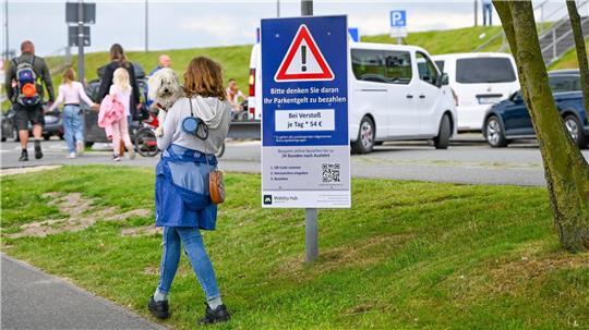 Diese Passantin schaut ganz genau hin: Auf dem Schild wird auf die teuren Knöllchen hingewiesen. 54 Euro kostet das Falschparken auf dem Parkplatz am Neuen Hafen.