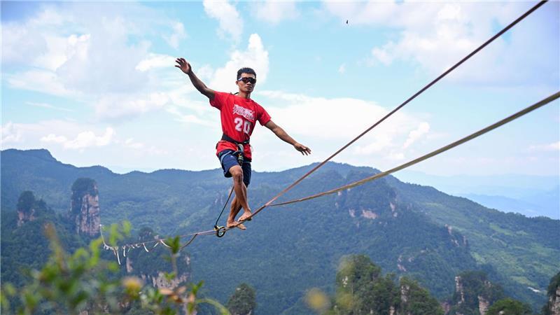 Dieses Drohnenfoto zeigt den den Chinesen He Jinyi bei der „Slackline-König“-Meisterschaft 2025 im malerischen Ort Huangshizhai im Zhangjiajie Nationalpark in der zentralchinesischen Provinz Hunan. 