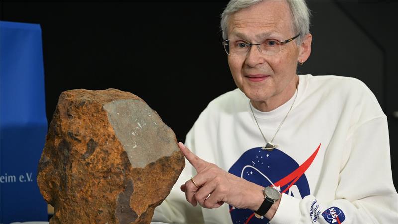 Dieter Heinlein, Meteoritenexperte des Deutschen Zentrums für Luft- und Raumfahrt (DLR), gibt neben einem Meteoriten ein Interview.