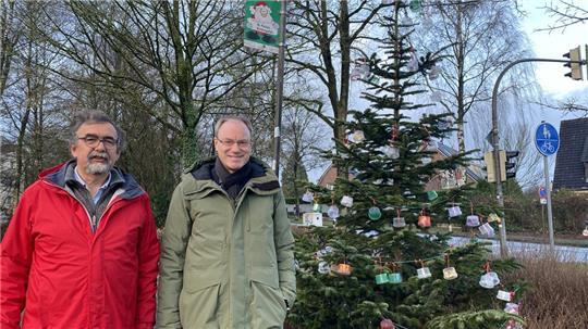 Dietmar Thoden und Jochen Lindemann stehen neben dem geschmückten Baum an der Apensener Straße