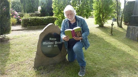 Dietrich Alsdorf mit seinem Buch am Grab von Marlene Prink auf dem Friedhof in Harsefeld.