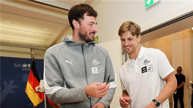 Wem Handball-Fan Günther die Daumen drückt Domagoj Duvnjak (l) und Rune Dahmke vom THW Kiel tragen sich in das Gästebuch der Landesregierung von Schleswig-Holstein ein.