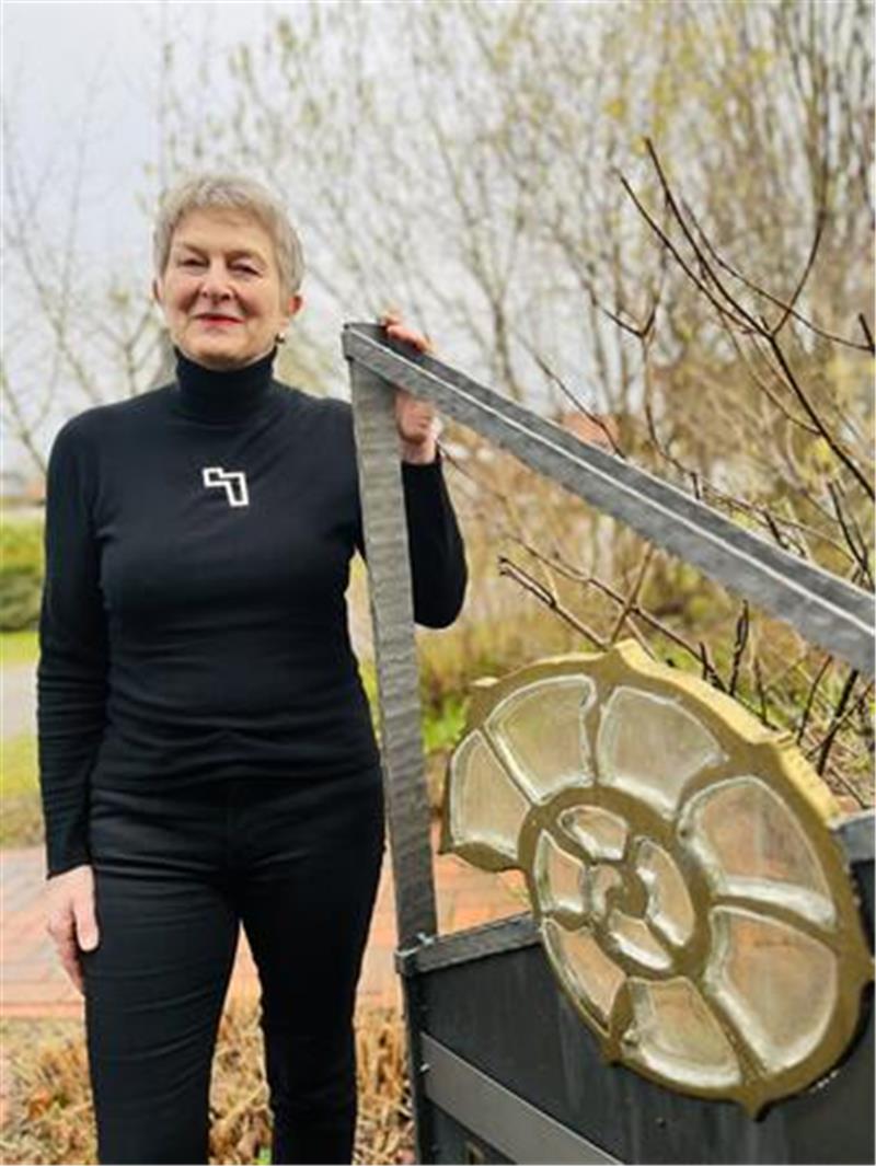 Doris von Lehe neben ihrem Logo, das einen spiralförmigen Ammoniten zeigt. Damit hatte sie früher an ihrer Goldschmiede in der Stader Poststraße geworben. Heute steht das Zeichen in Hemmoor.