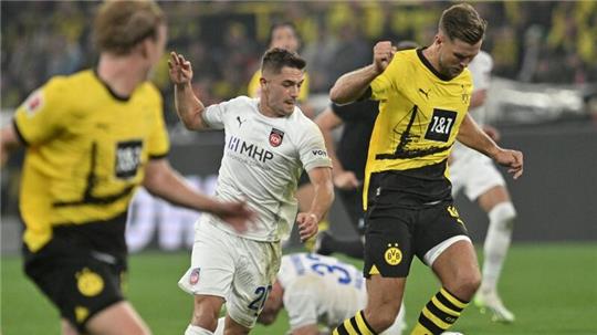 Dortmunds Niclas Füllkrug (r) und Heidenheims Nikola Dovedan (M) kämpfen um den Ball.