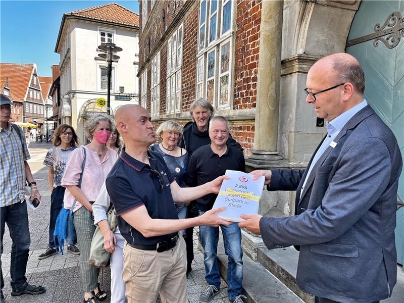 Dr. Bernd Hohendorff, umgeben von Mitstreitern der Bürgerinitiative, übergibt die Unterschriften an Sönke Hartlef. Foto: Richter