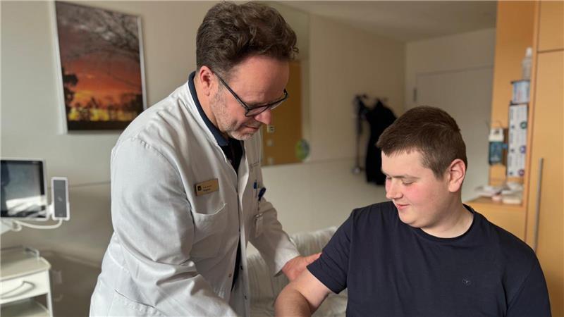 Dr. Matthias Priemel prüft, wie weit Tim Böckmann den Arm abwinkeln kann.