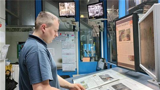 Draußen rauschen die bedruckten Papierbahnen vorbei. Am Leitstand kontrolliert und korrigiert Mattias Bauer das Ergebnis.