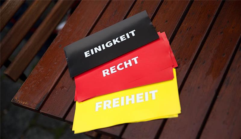 Drei Zettel mit den Aufschriften "Einigkeit", "Recht" und "Freiheit" liegen während der Feierlichkeiten zum Tag der Deutschen Einheit auf einem nassen Tisch vor der Frauenkirche. Symbolfoto: Arno Burgi/dpa-Zentralbild/dpa