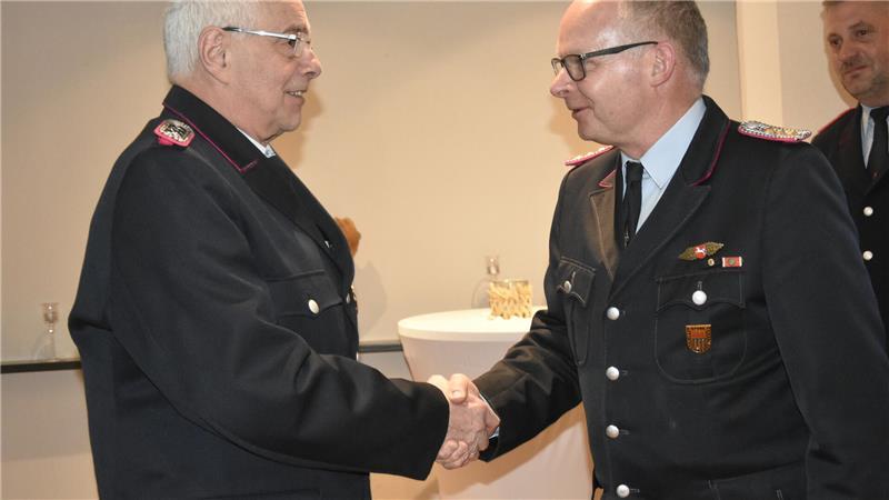 Drochtersens Gemeindebrandmeister Arnd König gratuliert Wilhelm Treudler zum 50-jährigen Dienstjubiläum.