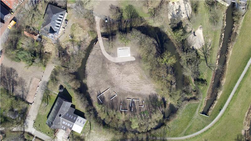 Drohnenaufnahme der Burginsel: Oben ist das Podest zu sehen. Unten sind Betonbänke zu erkennen, die die Wohn- und Wirtschaftsgebäude der Horneburg (1255 bis 1645) darstellen sollen. Links oben ist das Horneburger Schloss von 1886 zu sehen. Unten schließt das Handwerksmuseum an.