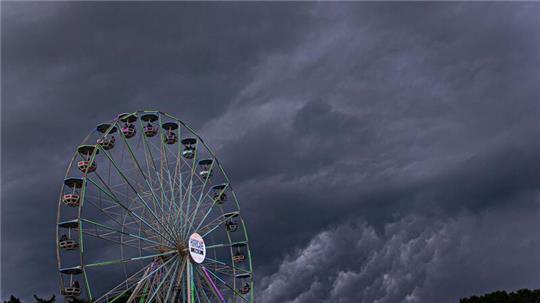 Dunkle Regenwolken ziehen über ein Riesenrad auf dem Gelände des Hurricane-Festivals in Scheeßel hinweg.