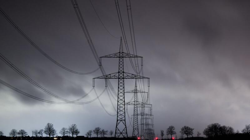 Wind und milde Temperaturen zum Wochenstart Dunkle Wolken ziehen über eine Hochspannungsleitung hinweg.