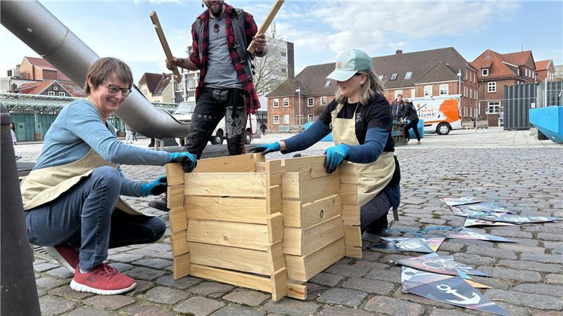 Ehrenamtliche vom Garten-Team bauen am Ankerplatz einen Behälter für Kompost auf.