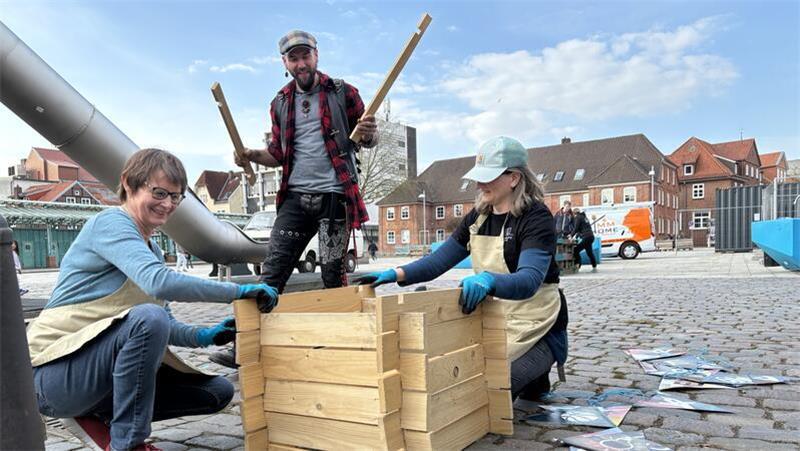 Ehrenamtliche vom Garten-Team bauen einen Behälter für Kompost auf.
