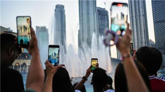 Eid al-Adha in Dubai: Besucher fotografieren den Brunnen vor der Skyline