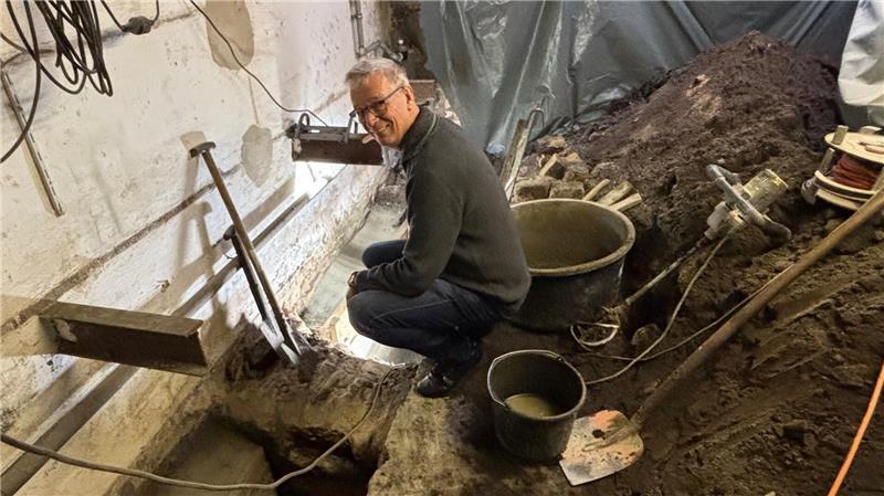 Eigentümer Gerd Meyer besichtigt die Baustelle im Keller seines Gebäudes in der Buxtehuder Altstadt. Handwerker errichten Fundamentstreifen aus Beton.