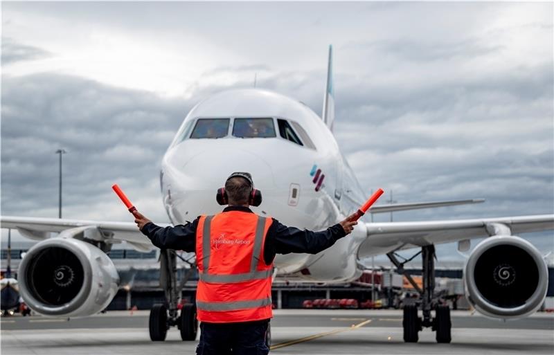 Ein Airbus 319 von Eurowings wird von einem Mitarbeiter des Flughafens auf dem neuen Vorfeld eingewiesen. Foto: Heimken/dpa
